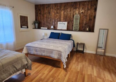 bedroom with two beds, wood floors, window, night stands, and wooden decor.